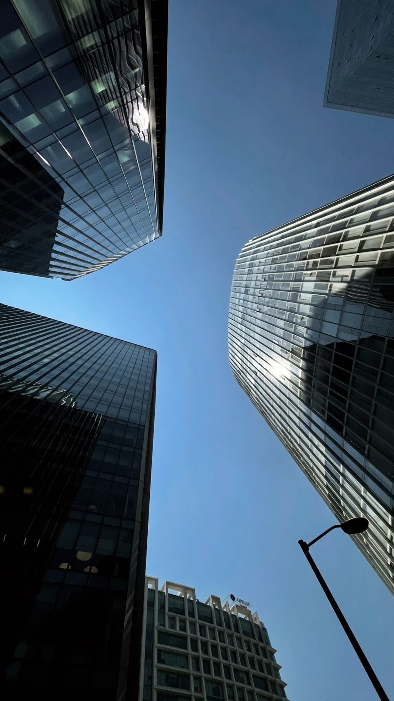 Glass towers framing a clear blue sky from below