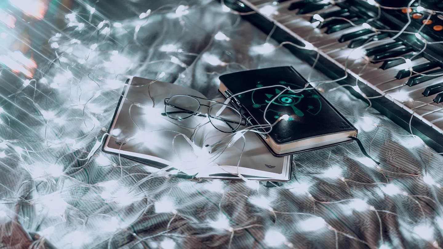 Notebooks, glasses and a keyboard wrapped in white lights