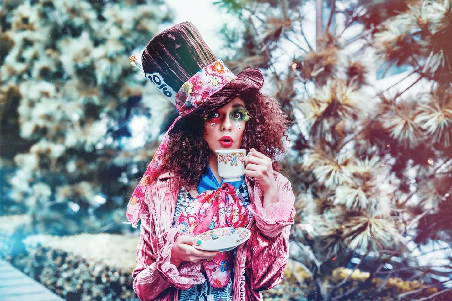 Theatrical Mad Hatter portrait holding a teacup in a wooded setting