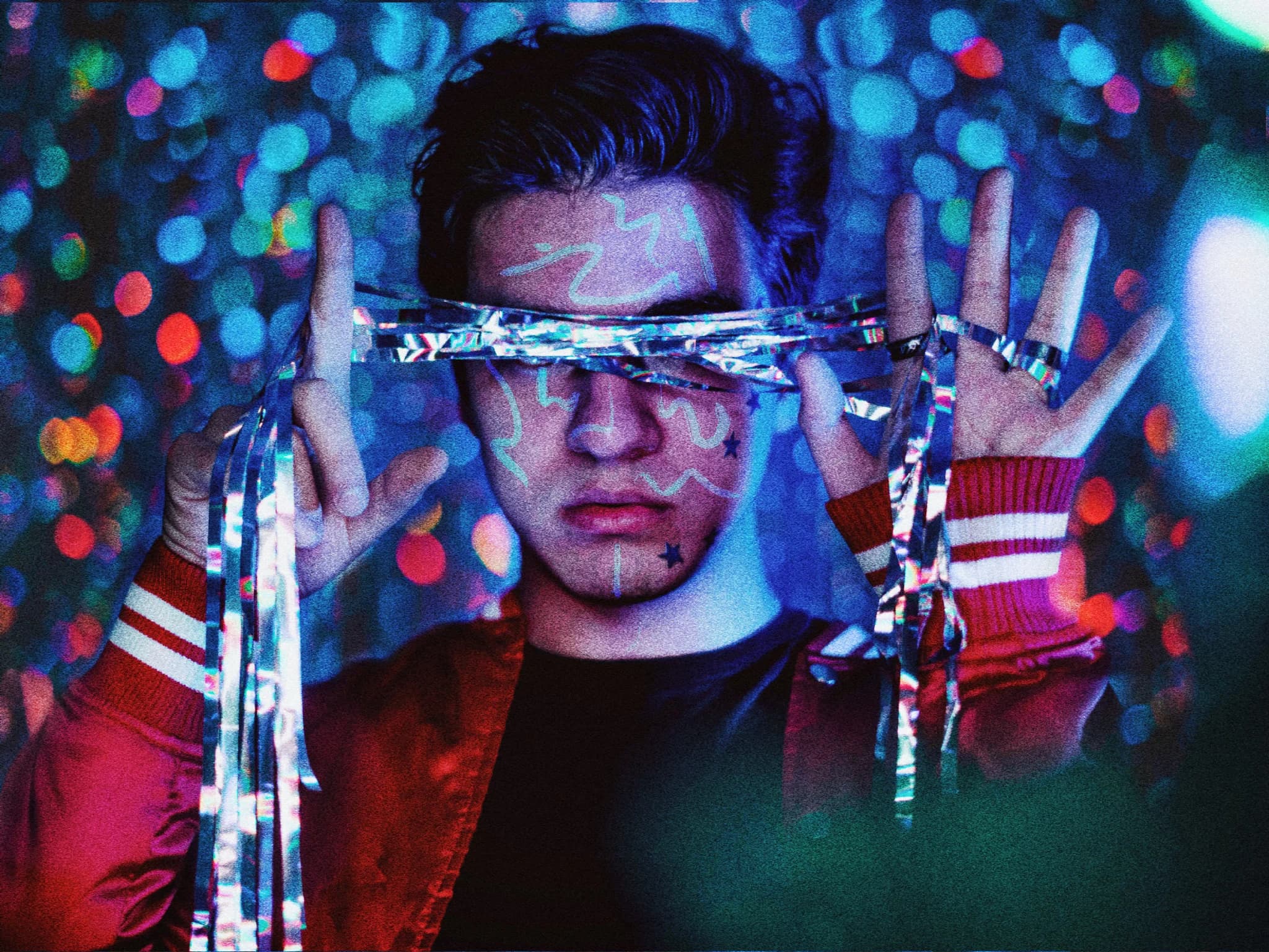 Portrait of a man holding reflective strips in a colorful, grainy setting