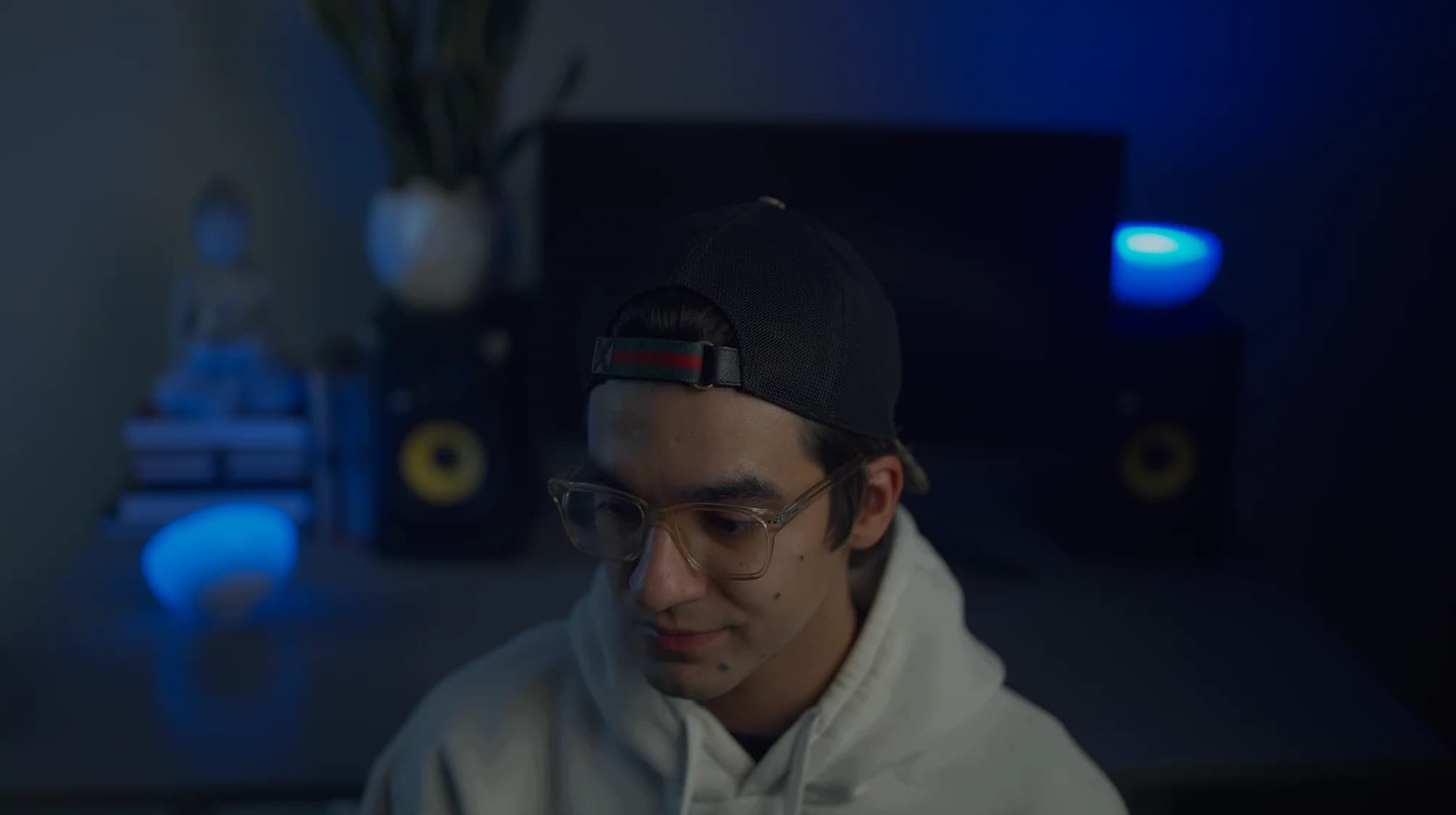 Portrait of a photographer wearing a cap and glasses in a blue-lit studio